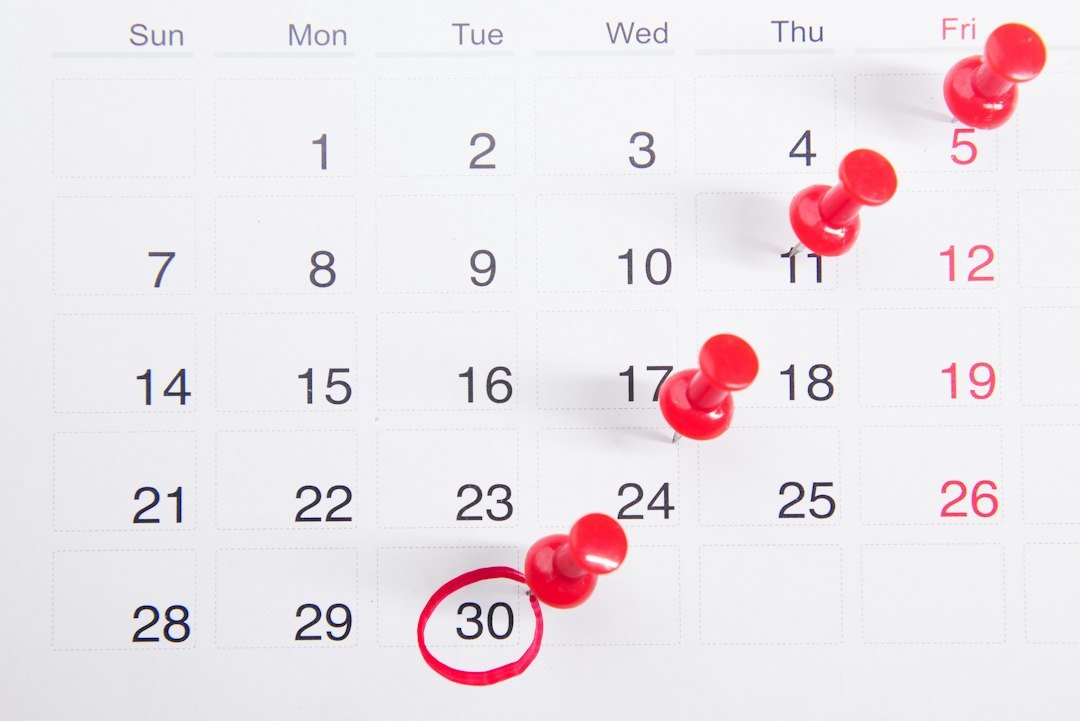 A close-up of a numbered calendar with red thumbtacks marking specific dates, emphasizing an important renewal date.